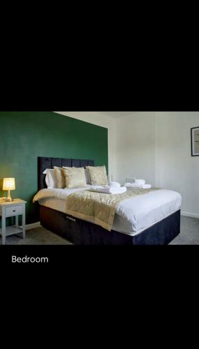 a bedroom with a large bed with a green wall at Spacious 3 bedroom house in nottingham in Nottingham