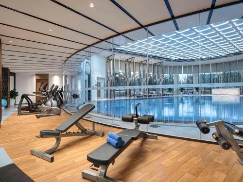 a gym with a swimming pool and some exercise equipment at Swissôtel Hefei Grand Park in Hefei