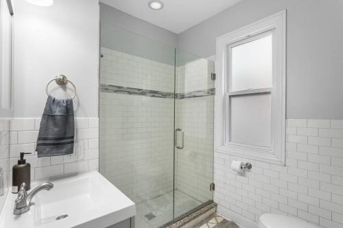 a white bathroom with a shower and a sink at Game Day Getaway - 3BR in Vibrant Wrigleyville in Chicago