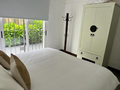 a bedroom with a white bed with a dresser and a window at IPB La Juanita Este in José Ignacio