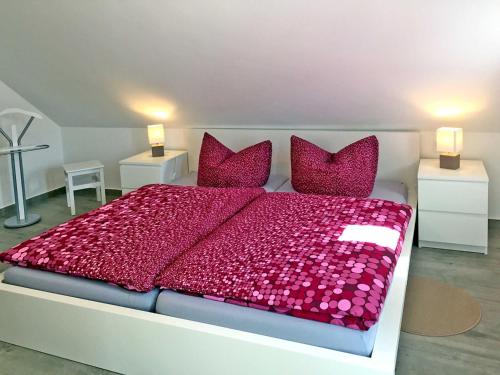 a bedroom with a large bed with red sheets and pillows at Ferienwohnung Le Papillon in Kröslin