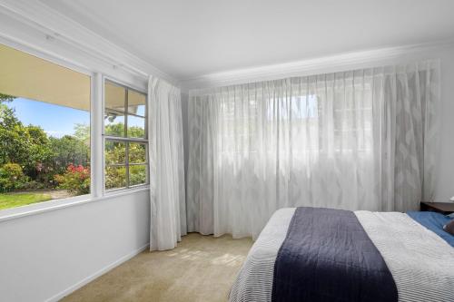 a bedroom with a bed and a large window at Maratoa - Takaka Holiday Home in Takaka