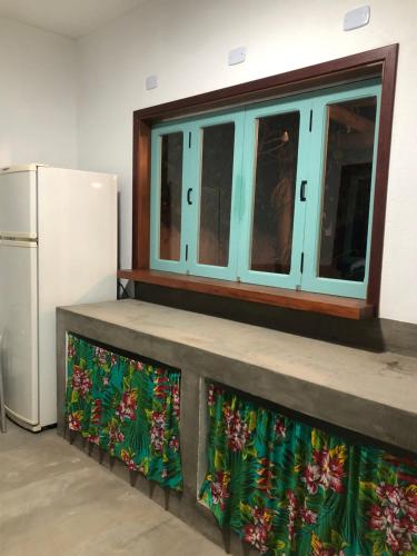 a kitchen with a counter with a window and a refrigerator at Casa Serrinha - Lindo e Espaçoso Chalé in Bueno Brandão