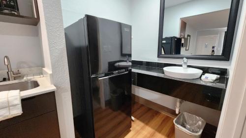 a bathroom with a black refrigerator and a sink at Studio 6 Webster TX Houston NASA Lake in Webster