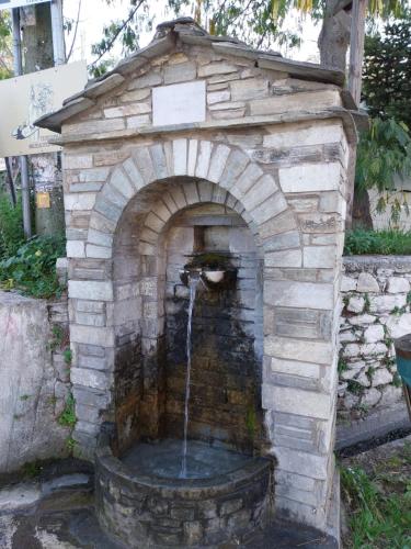 a stone fireplace with a water fountain in a yard at Marousos Central Guesthouse in Portariá