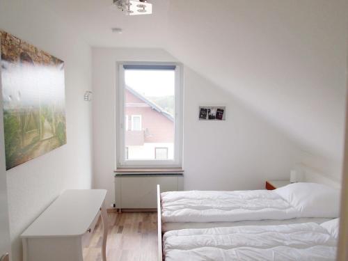 een witte slaapkamer met een bed en een raam bij Ferienwohnung Schimmer 27 in Braunlage