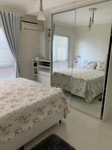a bedroom with two beds and a mirror at Pe na areia frente mar in Balneário Camboriú