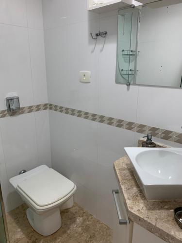 a white bathroom with a toilet and a sink at Pe na areia frente mar in Balneário Camboriú