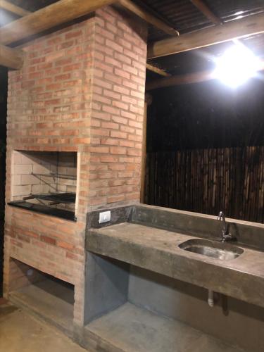 a kitchen with a brick fireplace and a sink at Casa Serrinha - Lindo e Espaçoso Chalé in Bueno Brandão