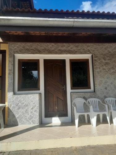 une maison avec deux chaises blanches et une porte en bois dans l'établissement Casa Chales Família Reis, à Ilhabela