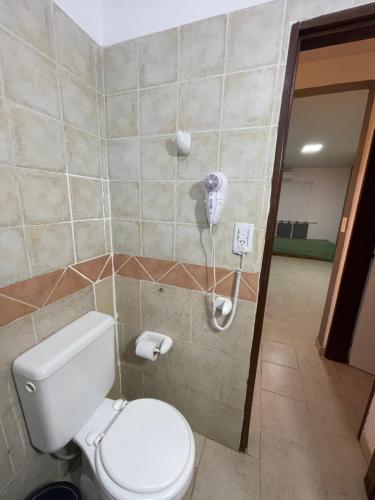 a bathroom with a toilet and a phone on the wall at Bungalows palmar in Chajarí