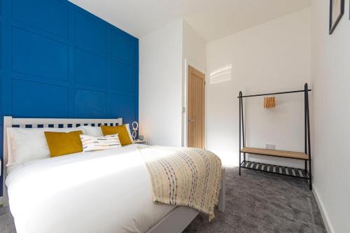 - une chambre avec un grand lit blanc et un mur bleu dans l'établissement Explore Welsh Wonders at The Panache Stay, à Nelson