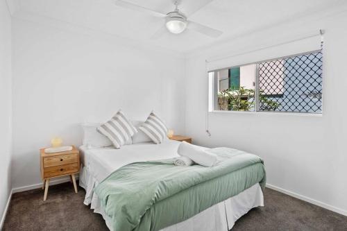 a white bedroom with a bed and a window at Bilinga Beach House in Gold Coast