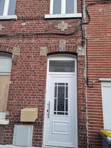 - un bâtiment en briques avec une porte blanche dans l'établissement Studio entièrement rénové proche gare, à Cambrai