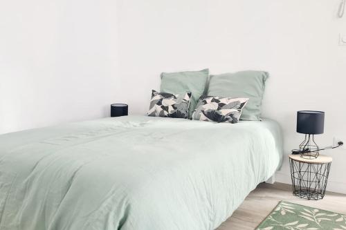 Una cama blanca con dos almohadas encima. en Studio entièrement rénové proche gare, en Cambrai