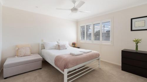 a white bedroom with a bed and a window at Bombora at Kiama in Kiama