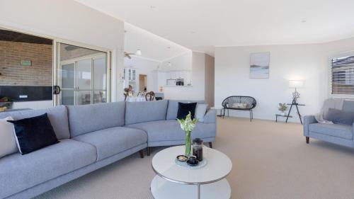 a living room with a blue couch and a table at Bombora at Kiama in Kiama