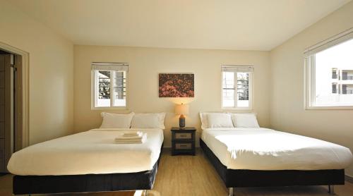 two beds in a room with two windows at Tumon Isa 16 Condo in Tamuning