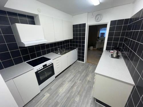 a kitchen with white appliances and black tiles on the wall at Bakgårdens Vandrarhem in Mariestad