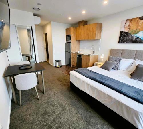 a bedroom with a bed and a table and a kitchen at The Residences Ellerslie in Auckland