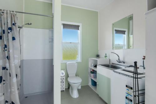 a white bathroom with a sink and a toilet at Pickers Cottage - Mapua Holiday Unit in Upper Moutere