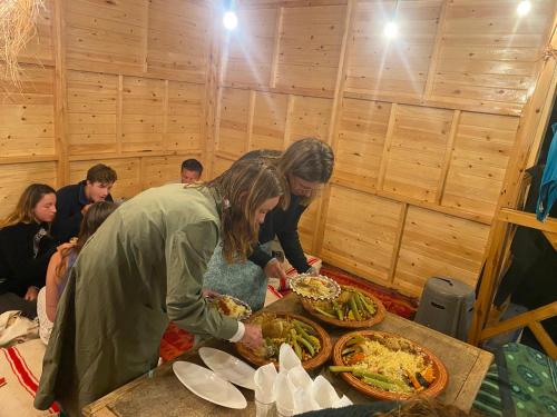 a group of people standing around a table with pizzas at West coast surf house in Imsouane