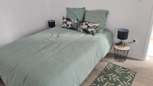 1 dormitorio con 1 cama grande con sábanas y almohadas verdes en Studio entièrement rénové proche gare en Cambrai
