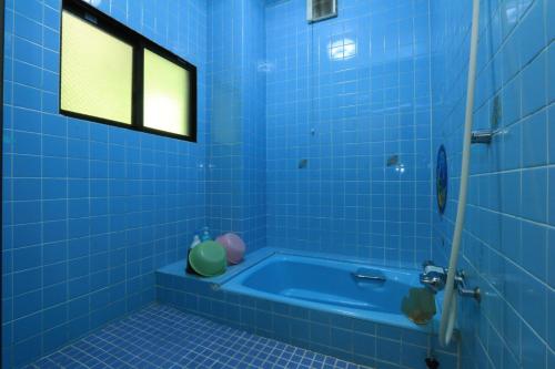 屋久島にある民宿 里町の青いタイル張りのバスルーム(窓のあるバスタブ付)