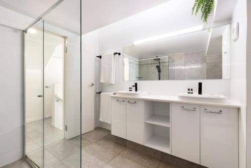バイロンベイにあるByron Bay Beachfront Holiday Apartments Penthouse 10の白いバスルーム(シンク2台、鏡付)