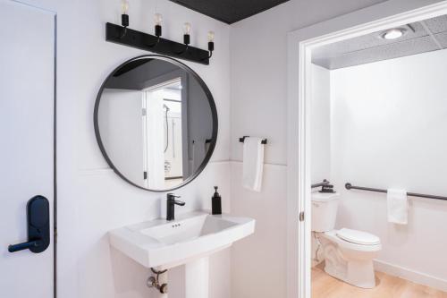 Baño blanco con lavabo y espejo en Trailhead by Weekender, 