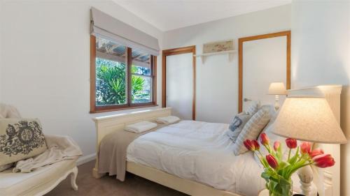 1 dormitorio con cama, ventana y silla en Cedar Cottage, en Canyonleigh