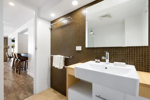 バイロンベイにあるByron Bay Beachfront Holiday Apartments Courtyard 6の白い洗面台と鏡のあるバスルーム
