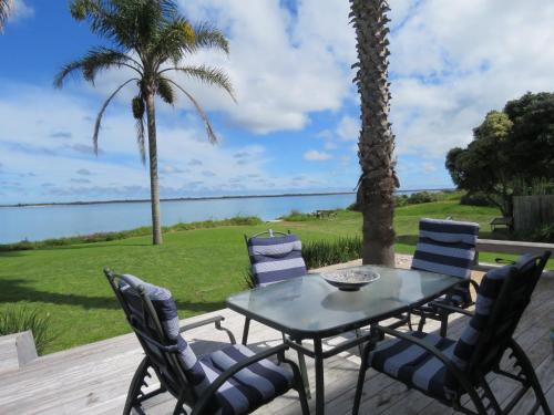a table and chairs on a patio with a view of the water at Rangiputa Moana in Karikari Peninsula