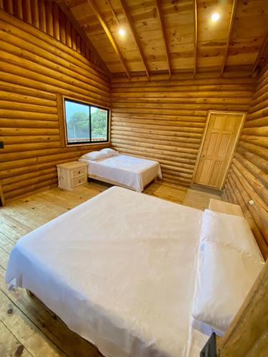 sypialnia z 2 łóżkami w drewnianym pokoju w obiekcie Cabañas Sierra Grande w mieście Santiago