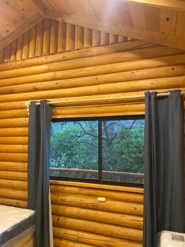 um quarto com uma janela num chalé de madeira em Cabañas Sierra Grande em Santiago