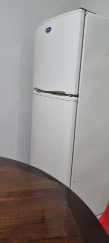 a white refrigerator sitting next to a wooden table at Departamento Planta Baja para 6 in Tampico