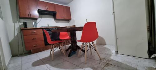 a kitchen with a wooden table and two red chairs at Departamento Planta Baja para 6 in Tampico