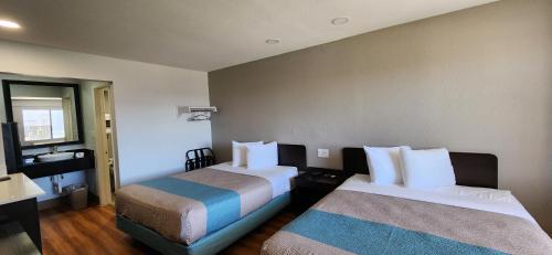 a hotel room with two beds and a mirror at Studio 6 Webster TX Houston NASA Lake in Webster