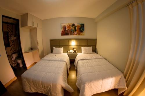 2 Betten in einem kleinen Zimmer mit in der Unterkunft Hotel Convencion in Trujillo