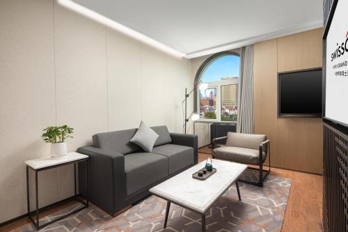 a living room with a couch and a tv at Swissôtel Hefei Grand Park in Hefei