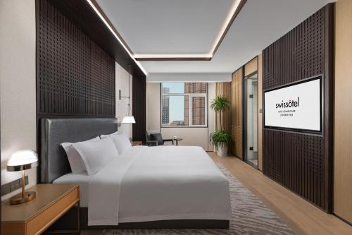 a hotel room with a bed and a tv at Swissôtel Hefei Grand Park in Hefei