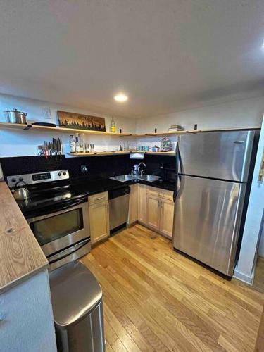 a kitchen with a stainless steel refrigerator and wooden floors at Affordable & Chic RiNo/LoDo/Dtown Loft- Walkable in Denver