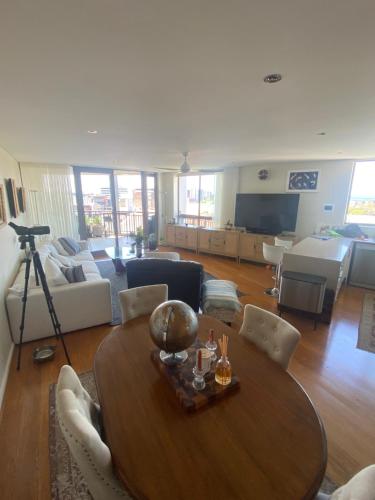 a living room with a wooden table and a couch at It's Paradise Here, Private Room with Breakfast and 2 cats in Wollongong