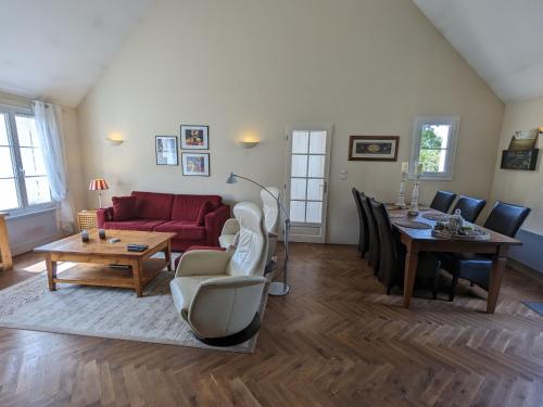 un salon avec un canapé rouge et une table dans l'établissement Gîte lumineux au calme avec jardin, golf, balades en forêt, barbecue et vélos à Donnery - FR-1-590-367, à Donnery