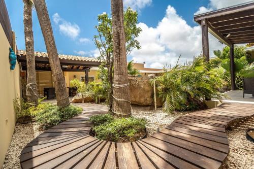 a wooden pathway with palm trees and a house at Juanedu Suites in Oranjestad