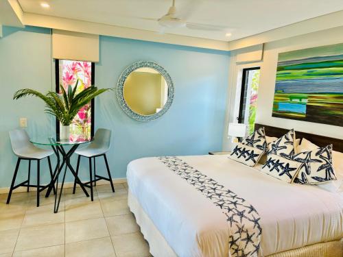 a blue bedroom with a bed and a table at Paradise Escape - Poolside Ground Floor - Sea Temple Resort and Spa in Port Douglas