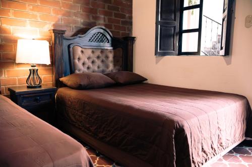 um quarto com uma cama, um candeeiro e uma parede de tijolos em Lar Antiqua Hotel em Quetzaltenango