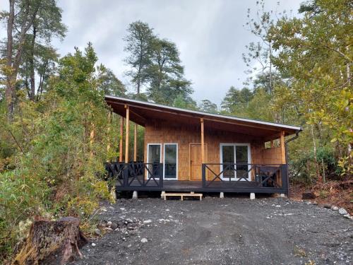 a cabin in the woods with a large porch at ENTRE BOSQUE in Puelo