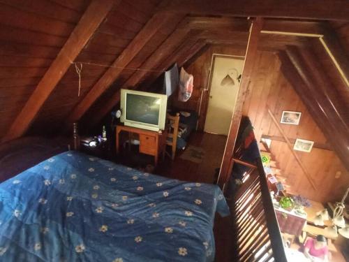 um quarto com uma cama e uma televisão num sótão em Casa en Liquiñe em Liquiñe