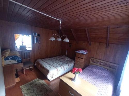 1 dormitorio con 2 camas y una mesa con flores en Casa en Liquiñe, en Liquiñe